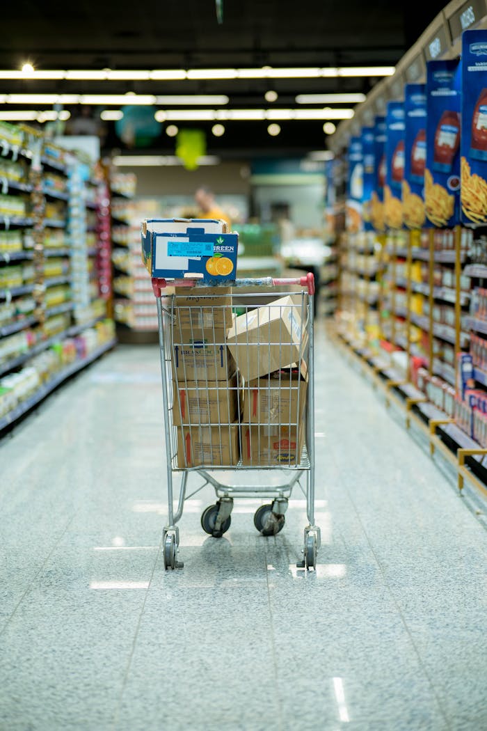 A shopping cart with packages in a grocery aisle, showcasing everyday shopping options.