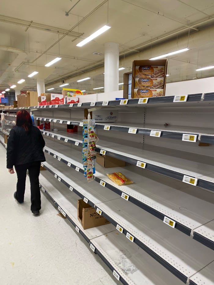 A shopper walks past nearly empty supermarket shelves during a stock shortage.